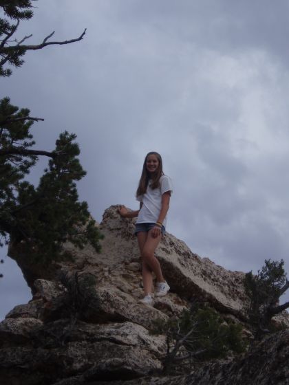 My sister on top of a tall rock pile near the Grand Canyon rim
